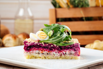 Russian dish Herring under a fur coat with greens on a light background