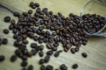 Roasted coffee beans spilled on wood with blurry details 