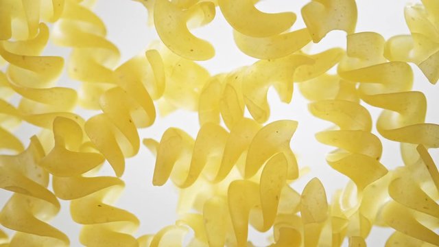 Slow motion of flying uncooked italian pasta. Fresh dry pasta fly down to the table. Slow motion