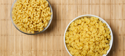 horizontal background - two bowls of dried pasta on a cane tablecloth