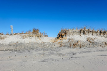 View from a sandy beach showing erosion with a path ending in a cliff