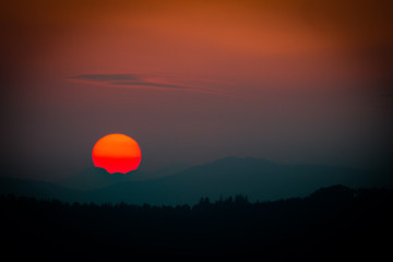 Sunset with disappearing sun over mountains