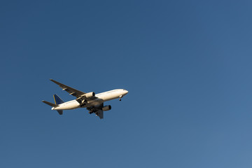 Fototapeta na wymiar White plane is preparing for landing. White plane in the blue sky.