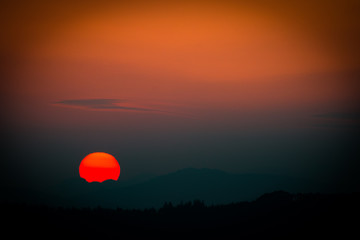 Obraz premium Sunset with disappearing sun over mountains