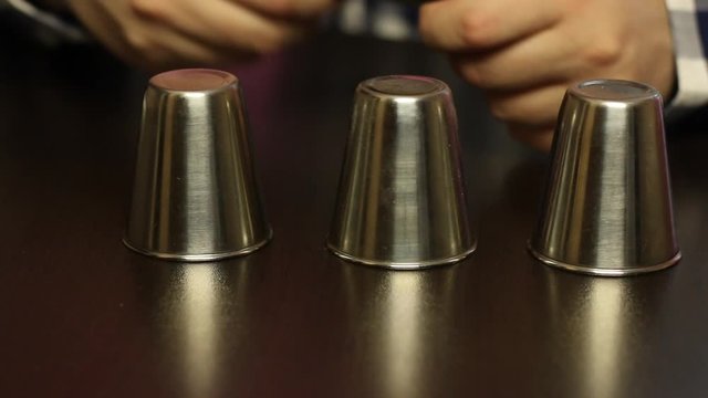 Thimblerig. The host prepares money and thimbles for the game. Close-up shot.