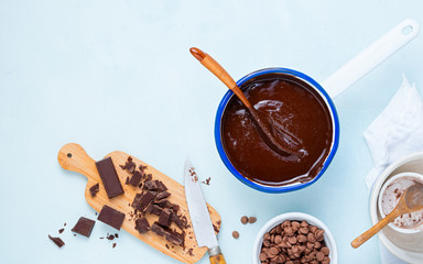 Dough preparation recipe cake, brownie, muffins, cupcakes ingridients, food flat lay on light blue background. Working with chocolate ganache, chocolate drops, chocolate, cocoa, sugar, bakery cooking.