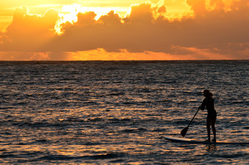 A Paddleboarder heads into the ocean to greet the Sunrise