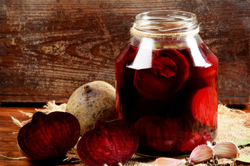 pieces of garlic, beets, spices next to the jar with pickled beets in the jar