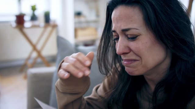 Crying depressed woman looking at photograph indoors, mental health concept.