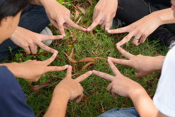 Group of friends forming fingers as star together as teamwork concept