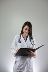 Female healthcare professional making note in patient's charge isolated on grey background