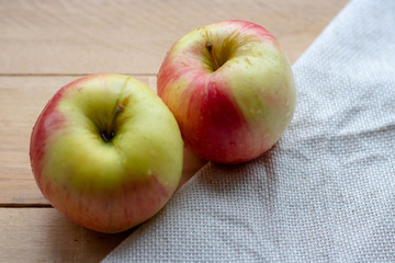 Ripe red-green apples on a wooden background with a napkin.