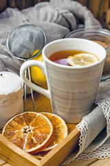 
A cup of black tea with lemon and spoon on a wooden table, next to a fresh lemon, sugar, closeup, copy space. Cozy background with a cup of tea and a slice of lemon