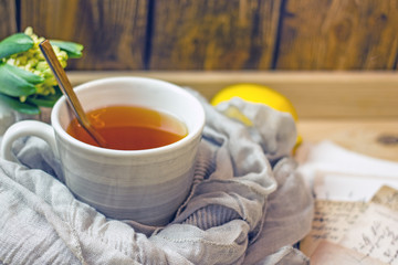 A cup of black tea with lemon and spoon on a wooden table, next to a fresh lemon, sugar, closeup, copy space. Cozy background with a cup of tea and a slice of lemon. Vertical background