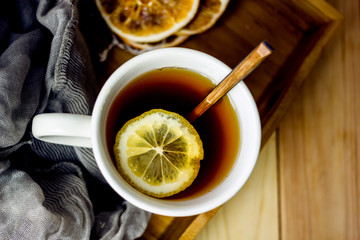 Hot black tea with a slice of lemon in a large gray mug with a spoon closeup, top view, next to...
