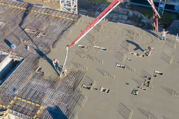 Pouring cement on the floors of residential multi-story building under construction using a concrete pump truck with high boom to supply the mixture to the upper floors. Aerial high top drone view. © aapsky