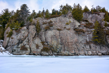 Fototapeta na wymiar Cliff with trees at the edge of a frozen lake