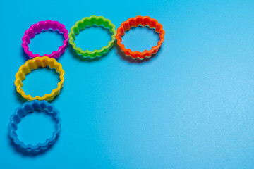Five multi-colored plastic cookie cutter for making cookies on a blue background. Culinary concept. Flat lay with copyspace.