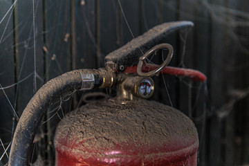 old fire extinguisher covered with dust and cobweb