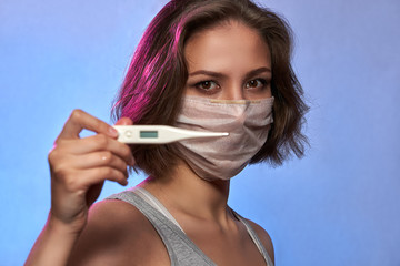 Covid-19 Pandemic Coronavirus Girl with protective mask on face and thermometer. Woman isolated on the light background in studio