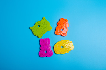 Five multi-colored plastic cookie cutter for making cookies on a blue background. Culinary concept....