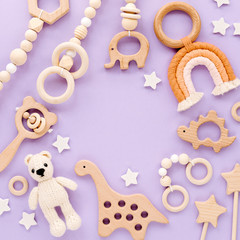 Cute wooden baby toys on light-blue background. Knitted bear, rainbow, dinosaur toy, beads and stars. Eco accessories,  beanbag and teethers for newborn. Flat lay, top view