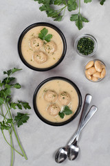 Bean cream soup with meatballs, dill, parsley in a bowl on a light background top view