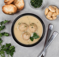 Bean soup-puree with meatballs, dill, parsley and croutons in a bowl on a light background top 