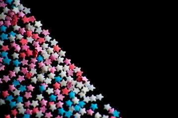 multicolored confectionery sprinkle in the form of stars on a black background