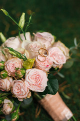 Bridal bouquet of roses and rings on natural background.