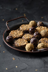 Healthy raw vegan sweets. Homemade energy bites with flax seeds in metal tray on black background