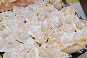 Dumplings, cooked at home, lie on a plate, sprinkled with flour.