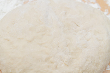 Prepared kneaded dough on a wooden table at home