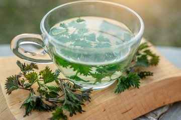 Cup of herbal tea with nettle on wooden background