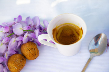 white cup of coffee with strawberries and purple flowers on a table ready for breakfast