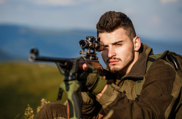 Fototapeta premium Hunt hunting rifle. Hunter man. Shooter sighting in the target. Hunting period. Male with a gun. Close up. Hunter with hunting gun and hunting form to hunt. Hunter is aiming. The man is on the hunt