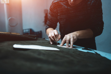 man shaping leather for shoe with knife on factory
