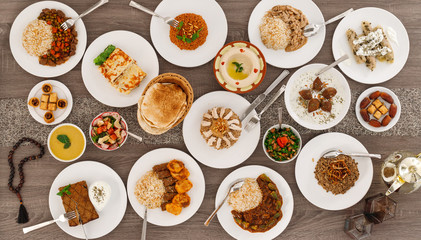 Iftar. Arabic family dinner. Ramadan Kareem, Eid Mubarak. Top view of table with sharing plates food. Lebanese cuisine. Starters, hummus, baklava, dates. Muslim people. - 339326057