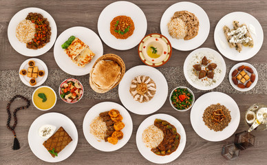Iftar. Arabic family dinner. Ramadan Kareem, Eid Mubarak. Top view of table with sharing plates food. Lebanese cuisine. Starters, hummus, baklava, dates. Muslim people. - 339326061