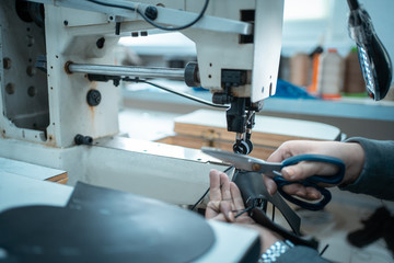 woman work with sewing machinery on shoe factory