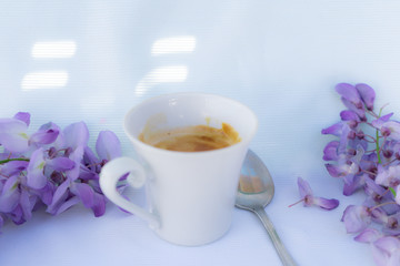 white cup of coffee with strawberries and purple flowers on a table ready for breakfast