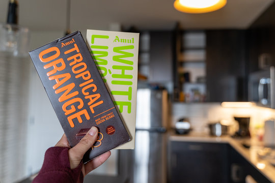Maple Grove, Minnesota - April 15, 2020: Hand holds two Amul brand chocolate bars in White Limon and Tropical Orange flavors