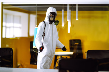 Disinfecting of office to prevent COVID-19, Man in protective hazmat suit with  with spray chemicals to preventing the spread of coronavirus, pandemic in quarantine city. Cleaning concept.