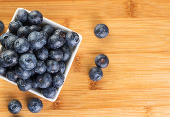 Fresh blueberry in white plate photographed against wooden background