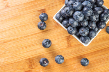 Fresh blueberry in white plate photographed against wooden background