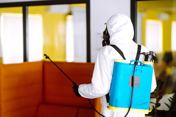 Disinfecting of office to prevent COVID-19, Man in protective hazmat suit with  with spray chemicals to preventing the spread of coronavirus, pandemic in quarantine city. Cleaning concept.