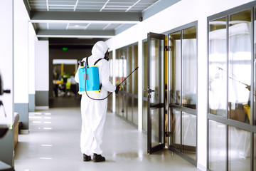 Disinfecting of office to prevent COVID-19, Man in protective hazmat suit with  with spray chemicals to preventing the spread of coronavirus, pandemic in quarantine city. Cleaning concept.