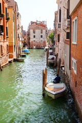 A venetian quiet channel with parked motor boats in summer day