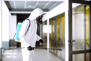 Disinfecting of office to prevent COVID-19, Man in protective hazmat suit with  with spray chemicals to preventing the spread of coronavirus, pandemic in quarantine city. Cleaning concept.