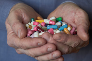 Multicolored pills in male hands, pharmacological and health protection concept.